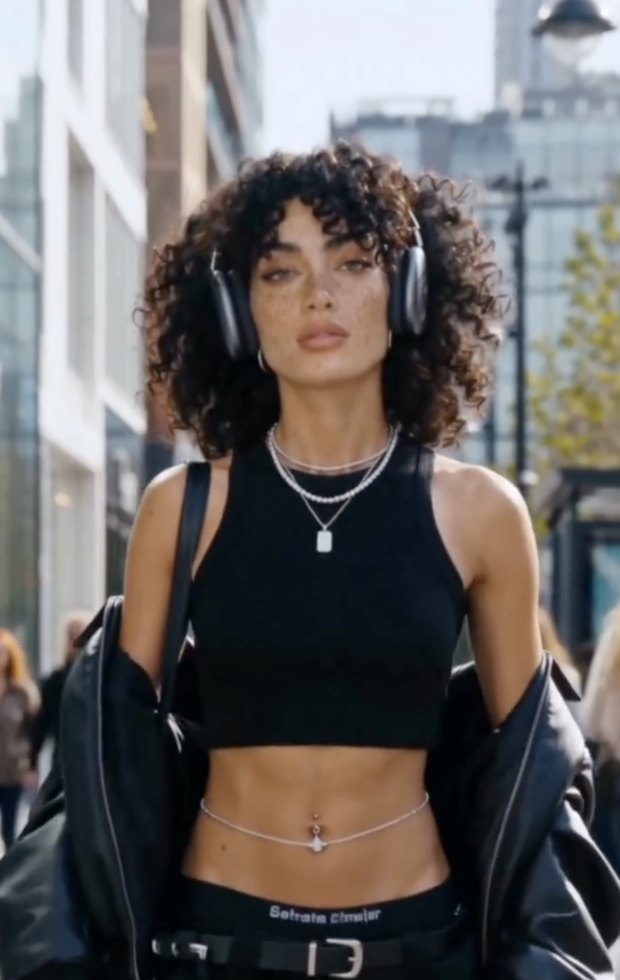 Layla Rey in a black crop top with headphones, walking through the city
